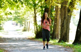 Frau spaziert auf einem sonnigen Waldweg mit Wasserflasche., © Donau Niederösterreich Tourismus, Steve Haider