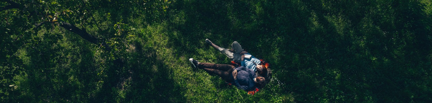 Ein Pärchen liegt im Grünen auf einer Picknickdecke.