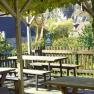 Gemütlicher Biergarten mit Holzbänken und Blick auf Dorf und Felsen., © Familie Pammer