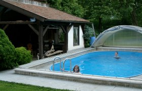 Überdachter Pool im Garten mit zwei schwimmenden Kindern., © Slavik