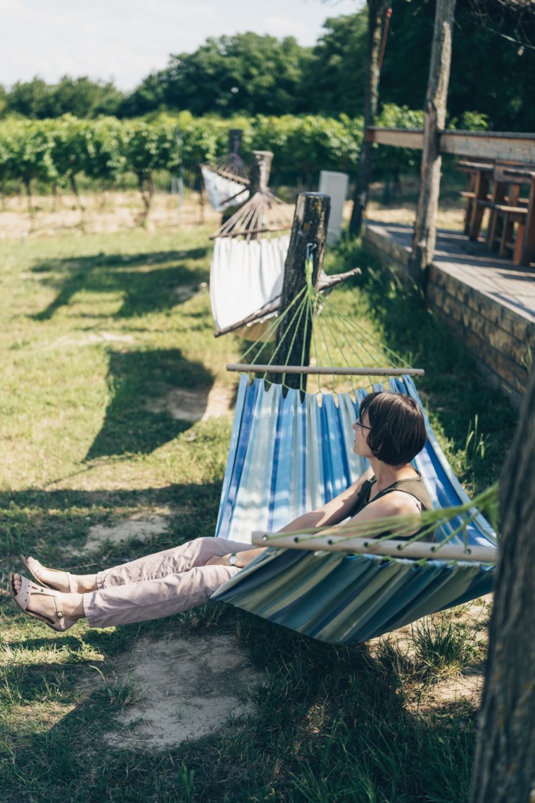 Frau liegt in Hängematte inmitten der Weinlandschaft