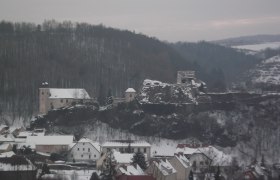 Winterliche Burgruine auf einem Hügel, umgeben von schneebedeckten Häusern., © Donau Niederösterreich