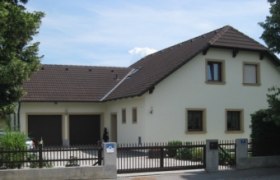 Einfamilienhaus mit Satteldach und Doppelgarage, umgeben von Bäumen., © Zelenka