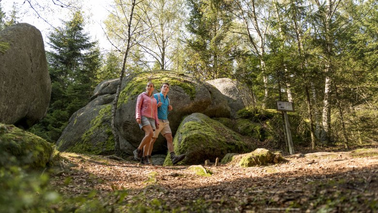 Wandernde gehen auf einem Wanderweg zwischen Steinen vorbei.