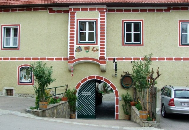 Historisches Gebäude mit Torbogen und Ziegelverzierungen, Pflanzen im Vordergrund., © Familie Leitner