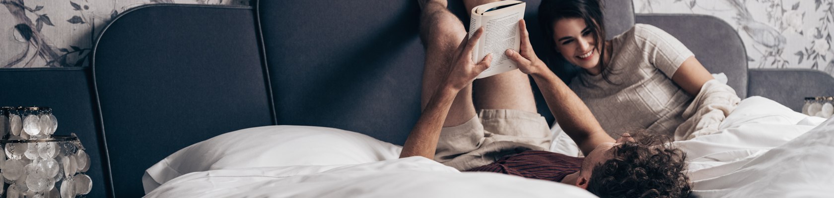 Ein Pärchen liegt im Bett. Er liest ein Buch.