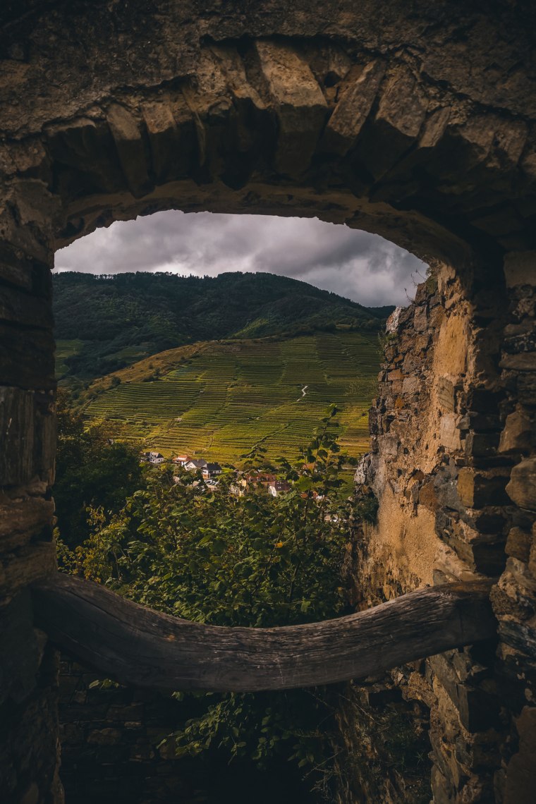 Fenster einer Ruine mit Ausblick auf Landschaft.