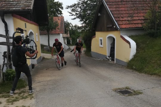 Parallel, genussvoll gelassen aber doch dynamisch vom Rad absteigen? Für unsere 2 Helden nach wenigen Versuchen kein Problem. Als Belohnung gab’s ein Achterl Grünen Veltliner Weinviertel DAC aus der Radlerrast (OK, wie viele es tatsächlich waren und wie oft wir die Gläser polieren mussten, bleibt Drehgeheimnis)., © Weinviertel Tourismus