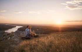 Paar sitzt bei Sonnenuntergang auf Hügel mit Flussblick., © Donau Niederösterreich, Andreas Hofer