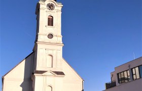 Kirchturm mit Uhr und Kreuz, daneben modernes Gebäude, blauer Himmel., © Donau NÖ Tourismus GmbH