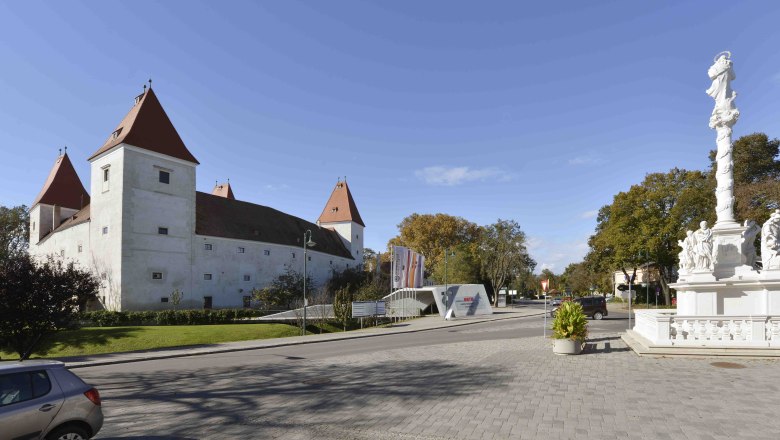 Historisches Schloss mit Türmen und barocker Säule im Vordergrund., © Donau Niederösterreich, Steve Haider