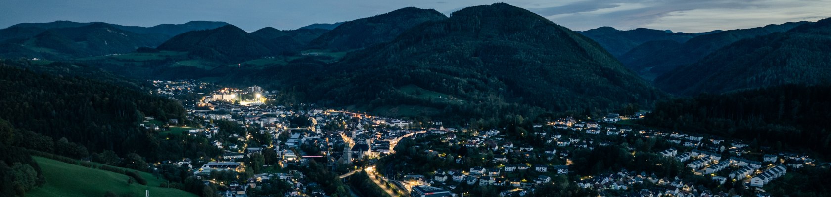 Waidhofen an der Ybbs von oben, beleuchtete Stadt eingebettet in grüne Hügellandschaft