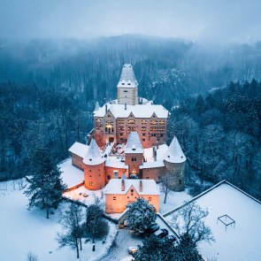 beleuchtete Burg bei Nacht auf Hügel mit schneebedeckter Landschaft